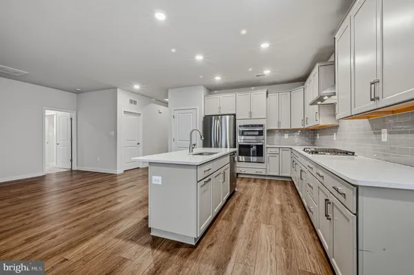 a large kitchen with stainless steel appliances granite countertop a large stove a sink dishwasher and a refrigerator with wooden floor
