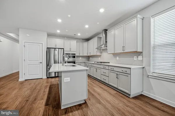a kitchen with stainless steel appliances granite countertop a stove a sink and white cabinets with wooden floor