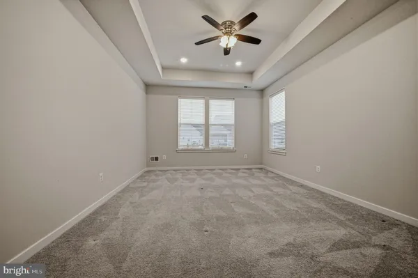 an empty room with windows and ceiling fan