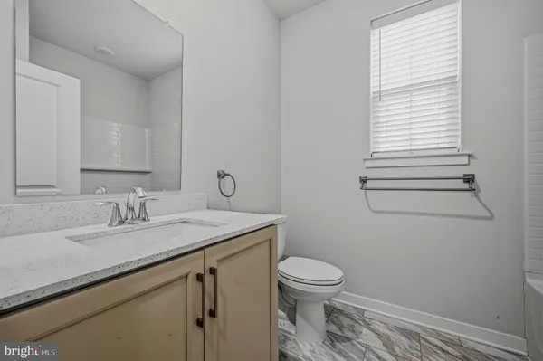 a bathroom with a granite countertop toilet sink and mirror