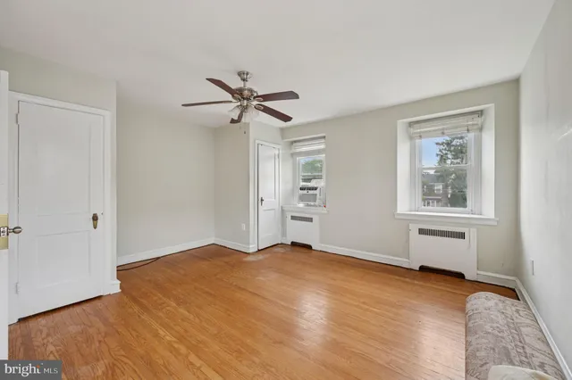 a view of an empty room with a window and wooden floor