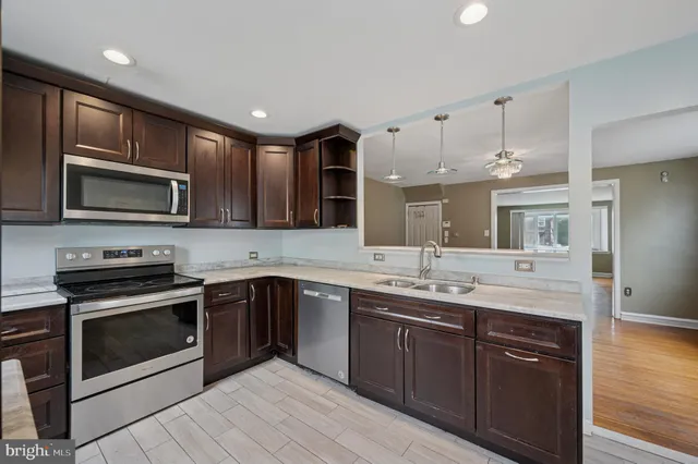 a kitchen with stainless steel appliances kitchen island granite countertop a sink stove and refrigerator
