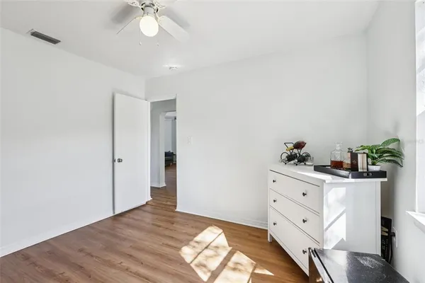 a view of a bedroom with wooden floor and ceiling fan