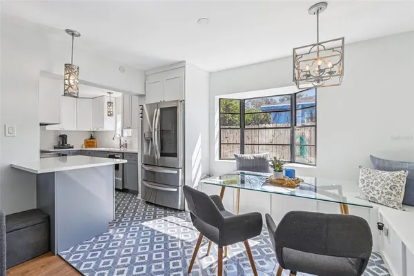 a kitchen with a refrigerator a stove a sink dishwasher a dining table and chairs with wooden floor