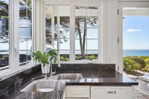 a living room with stainless steel appliances granite countertop furniture a couch a fireplace and a large window