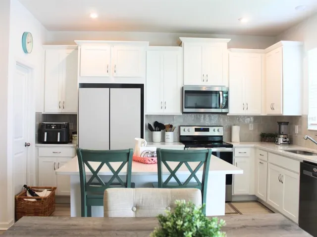 a kitchen with stainless steel appliances a stove a sink a microwave a refrigerator and cabinets