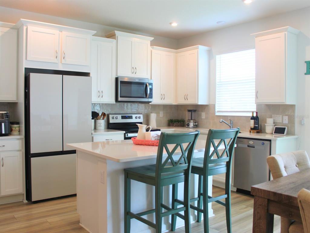 1005 Spring Palms Loop Orlando, FL 32828 - Photo 22 of 29 a kitchen with stainless steel appliances granite countertop a stove a sink a microwave a refrigerator with a dining table and chairs