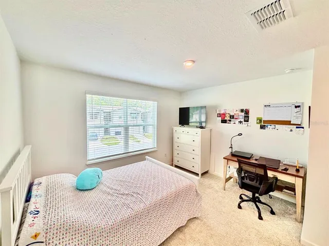 a bedroom with a bed a computer on the desk and chair