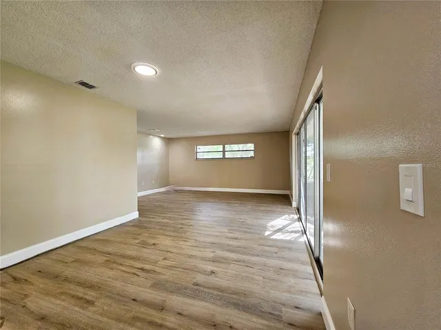 a view of empty room with window and wooden floor
