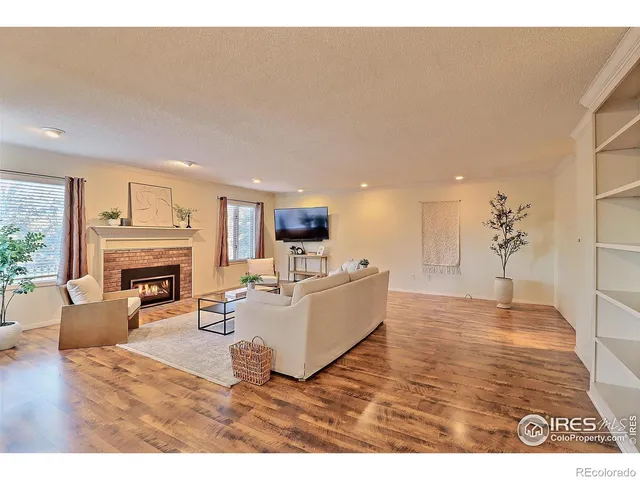 a living room with furniture a fireplace and a dining table with wooden floor