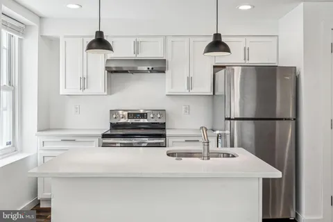 a kitchen with a refrigerator and white cabinets