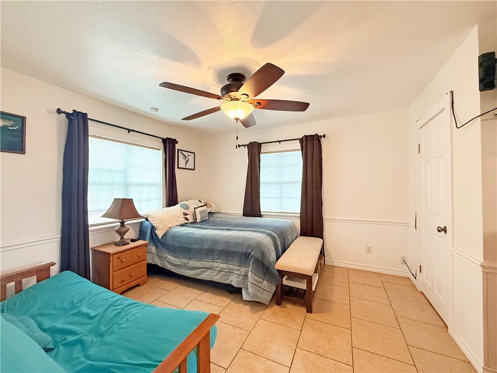 105 Copano Cove Road Rockport, TX 78382 - Photo 19 of 40 a bedroom with a bed and a chandelier
