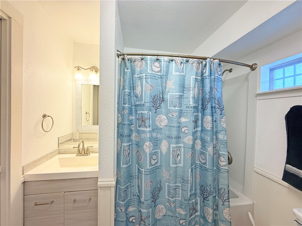 105 Copano Cove Road Rockport, TX 78382 - Photo 28 of 40 a bathroom with a shower curtain a sink and a large mirror