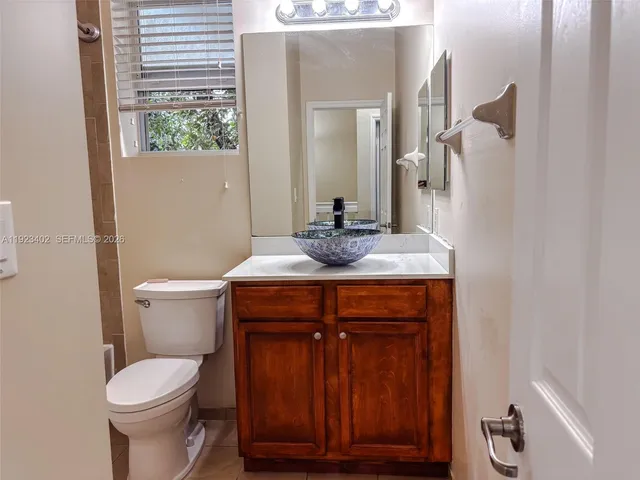 a bathroom with a granite countertop toilet and a sink