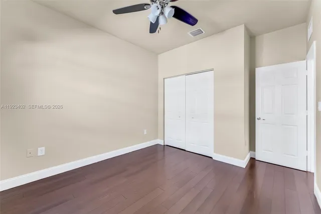 an empty room with wooden floor and ceiling fan