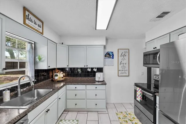 a kitchen with granite countertop a sink stove and refrigerator