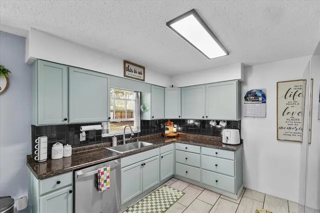 a kitchen with granite countertop a sink a stove and cabinets