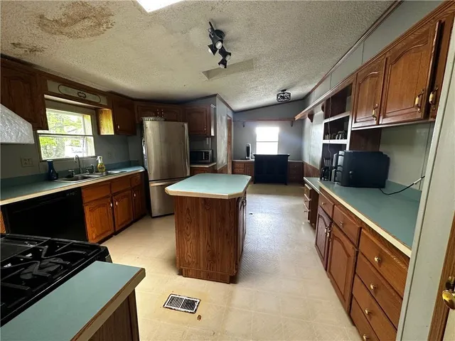 a kitchen with stainless steel appliances a stove a sink a refrigerator and a microwave