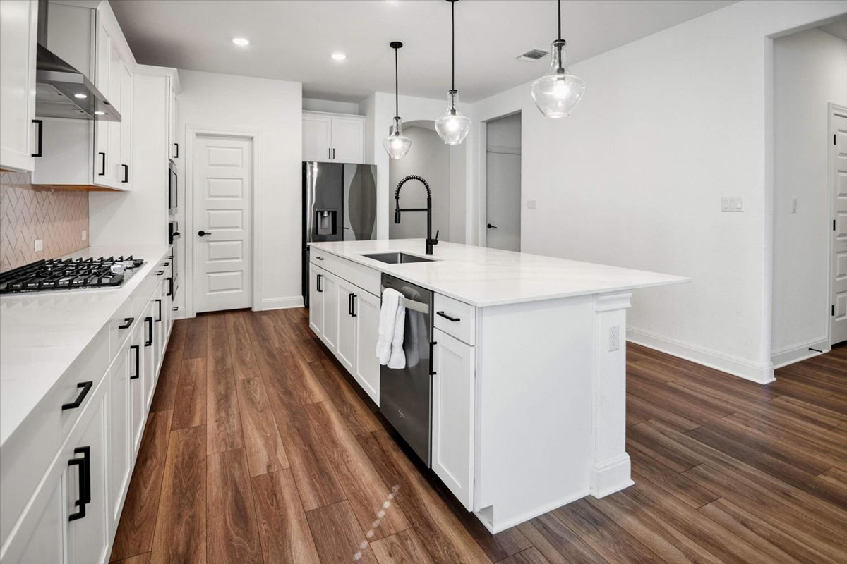 104 Raleigh Drive Georgetown, TX 78633 - Photo 15 of 37 Modern kitchen features a substantial center island and rich wood-look flooring.