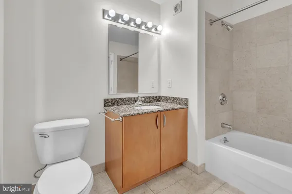 a bathroom with a granite countertop toilet a sink and a bathtub