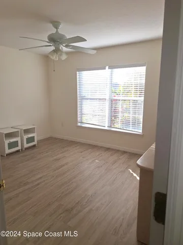 an empty room with wooden floor fan and windows