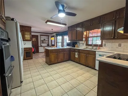 a kitchen with stainless steel appliances a sink a stove a refrigerator cabinets and a window