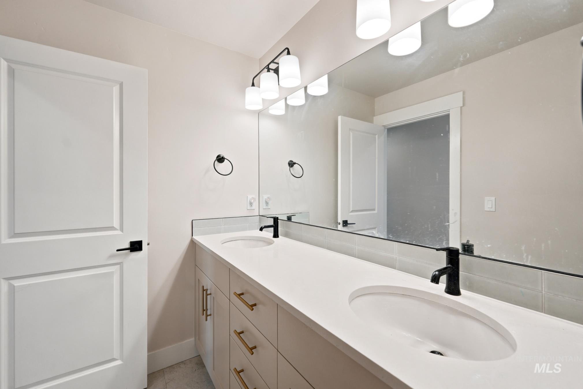 6933 South Zenith Avenue Meridian, ID 83642 - Photo 18 of 34 Dual sink vanity with white countertop, undermount sinks, and matte black faucets