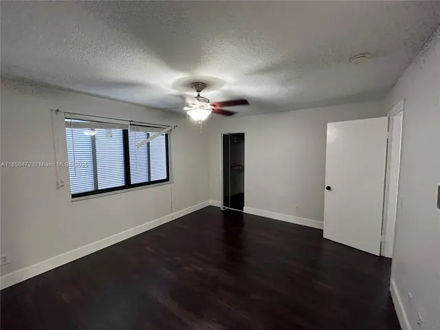 an empty room with wooden floor ceiling fan and window