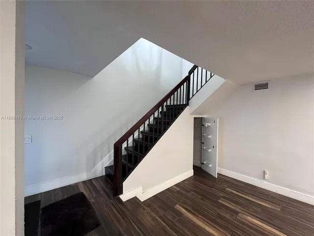 a view of an empty room with wooden floor and windows