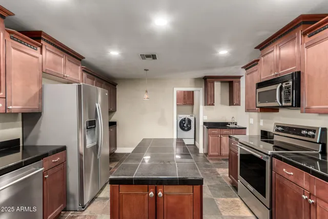 a kitchen with stainless steel appliances granite countertop a refrigerator a stove and a sink