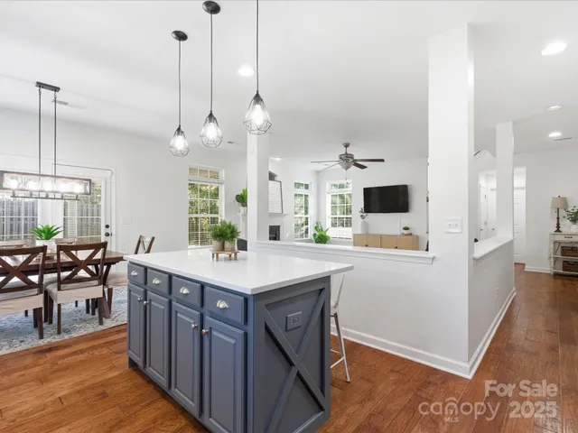 a kitchen with stainless steel appliances a stove a sink a kitchen island with chairs and wooden floor