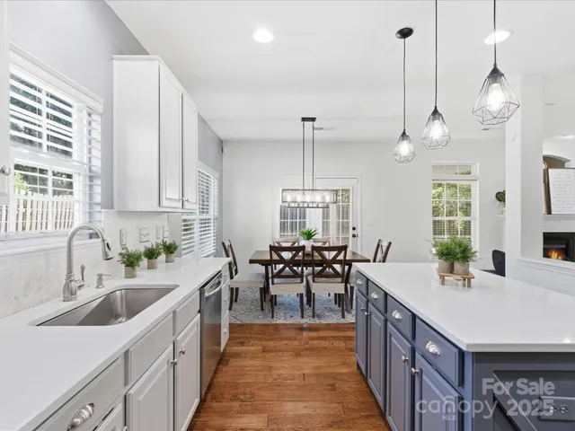 a very nice looking kitchen with granite countertop a sink a counter top space and living room view