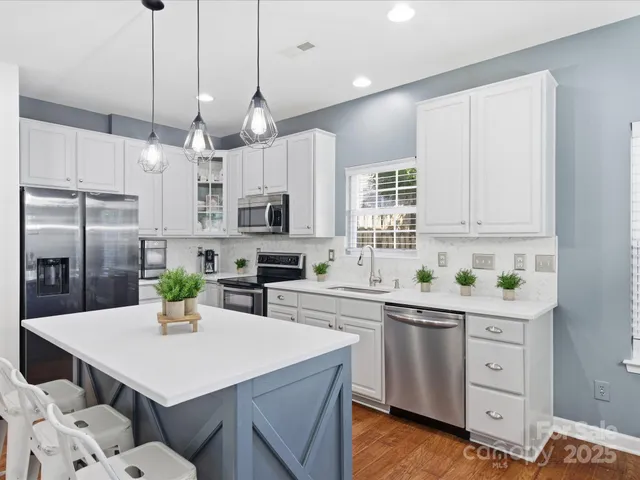 a kitchen with stainless steel appliances kitchen island granite countertop a sink a stove a dining table and chairs