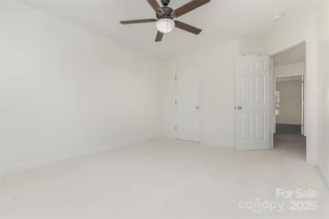 an empty room with a ceiling fan and a window