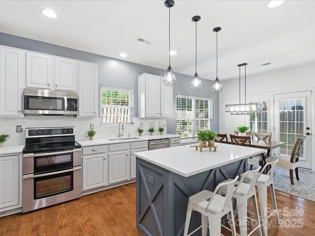 a kitchen with stainless steel appliances a stove center island a microwave and cabinets