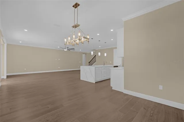 an empty room with wooden floor ceiling fan and windows