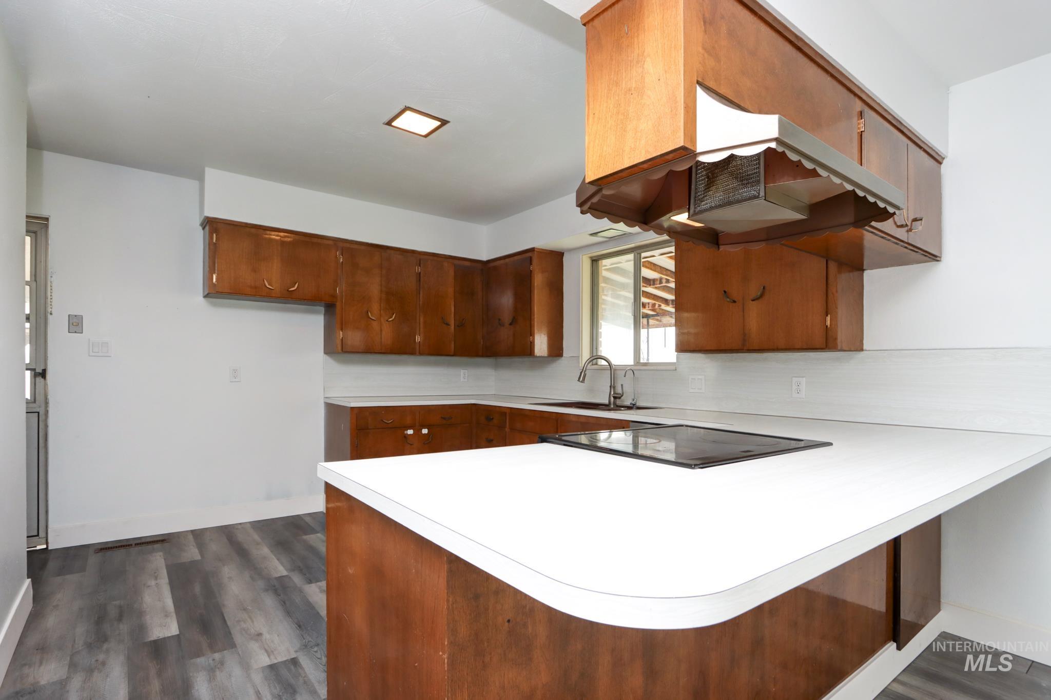 801 Thompson Avenue Nyssa, OR 97913 - Photo 9 of 46 Kitchen featuring wood-finish cabinetry, white countertops, a built-in cooktop, stainless steel sink, and wood-finish flooring
