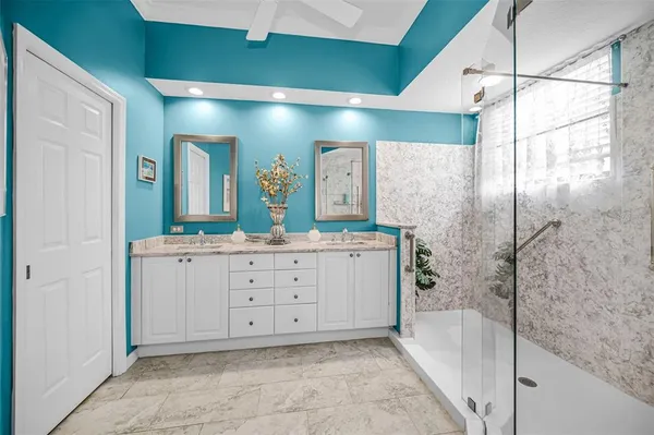 a spacious bathroom with a double vanity sink a mirror and a shower