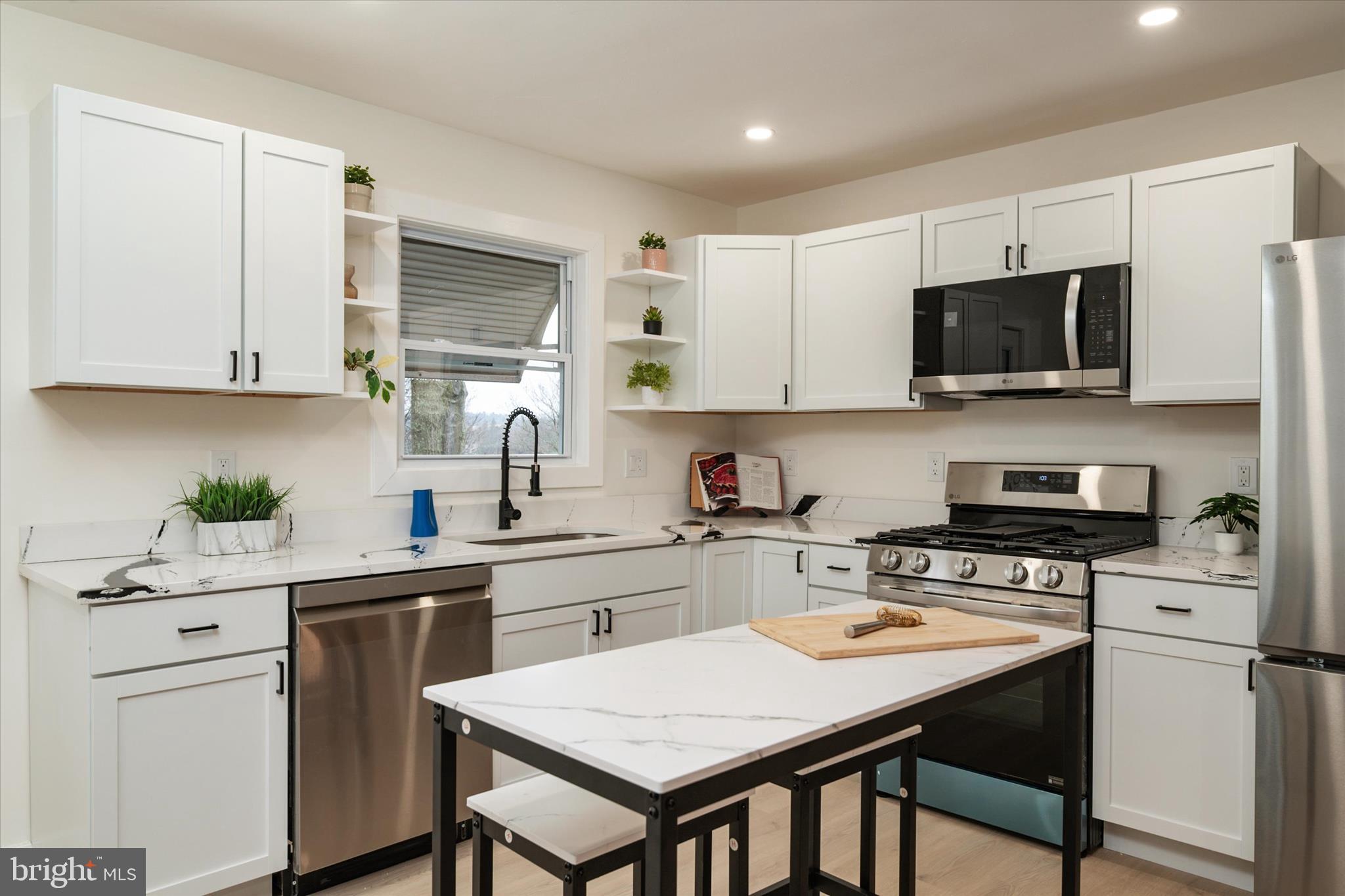 36 East George Street Westminster, MD 21157 - Photo 7 of 33 a kitchen with stainless steel appliances a stove a sink a refrigerator white cabinets and a chairs