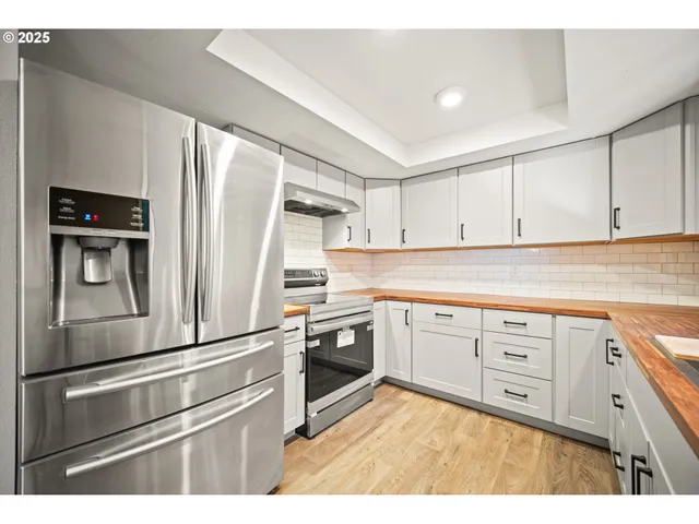 a kitchen with granite countertop white cabinets white stainless steel appliances and refrigerator