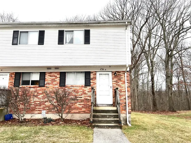 a front view of a house with a large tree
