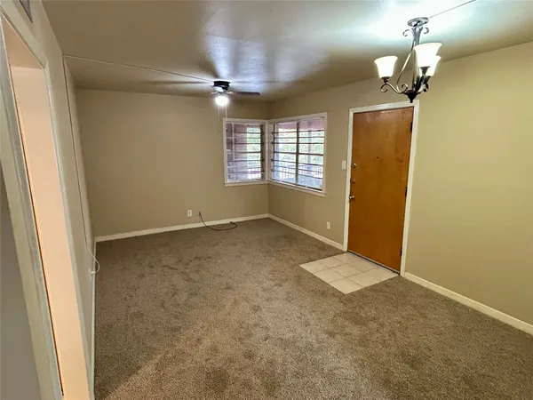 en empty room with a chandelier fan and windows