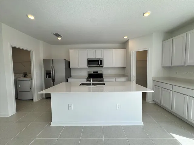 a view of kitchen with stainless steel appliances granite countertop a sink a stove a refrigerator and cabinets