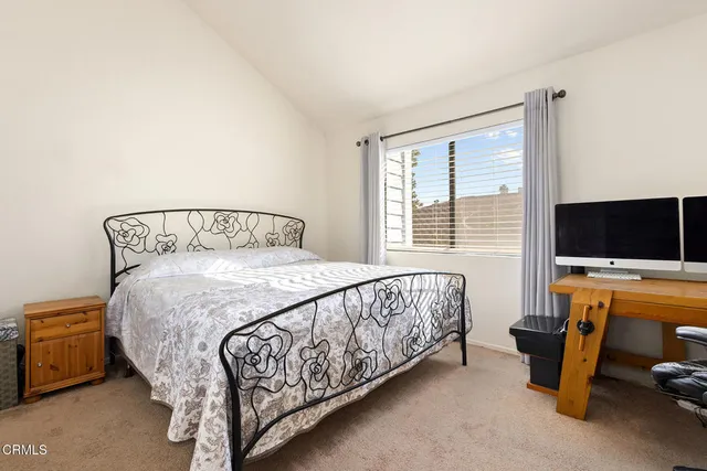 a bed sitting in a bedroom next to a flat tv screen and a larger window