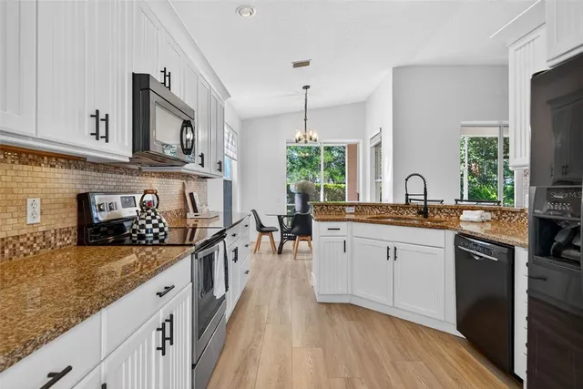 a kitchen with granite countertop white cabinets white stainless steel appliances with a sink and dishwasher