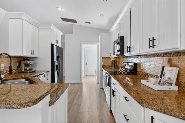 a kitchen with stainless steel appliances granite countertop a stove a sink and a white cabinets