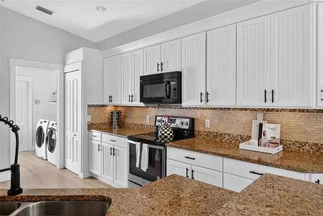 a kitchen with stainless steel appliances granite countertop a stove top oven a sink a dining table and chairs with wooden floor