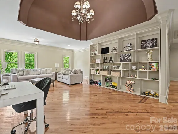 a living room with furniture a chandelier and a dining table with wooden floor