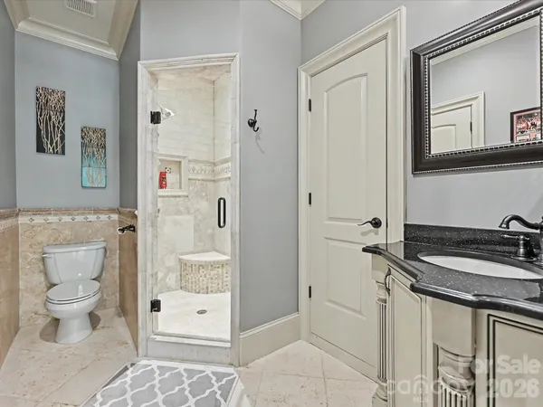 a bathroom with a granite countertop sink a toilet a mirror and shower