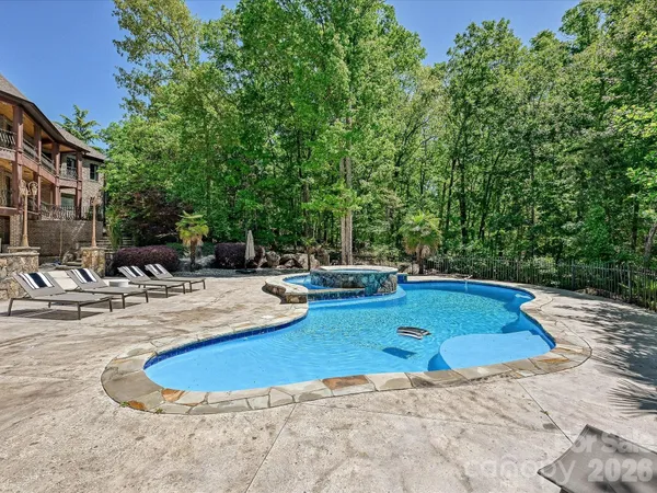a view of pool with lawn chairs and plants